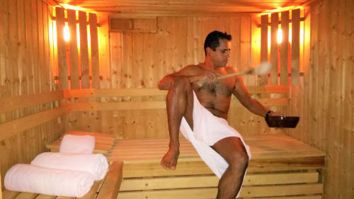 Man relaxing in wooden sauna with warm lighting at La Bergerie Du Moulin, a French bed and breakfast in Taradeau