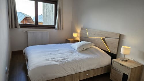 Chambre moderne à l'hôtel L'écrin des sapins à Aime-la-Plagne avec lit en bois, literie blanche et vue sur les montagnes