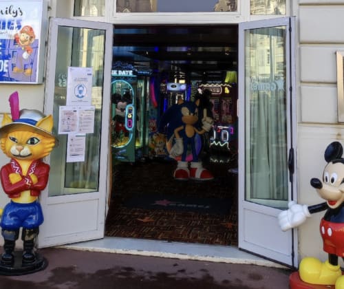 Entrée colorée de galerie de jeux d'arcade à Trouville-sur-Mer avec figurines vintage et enseignes néon