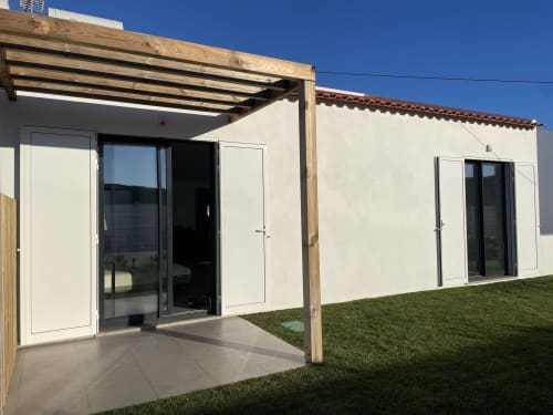 Modern white bungalow with wooden pergola and glass doors at Star Host in Bordeira, Portugal