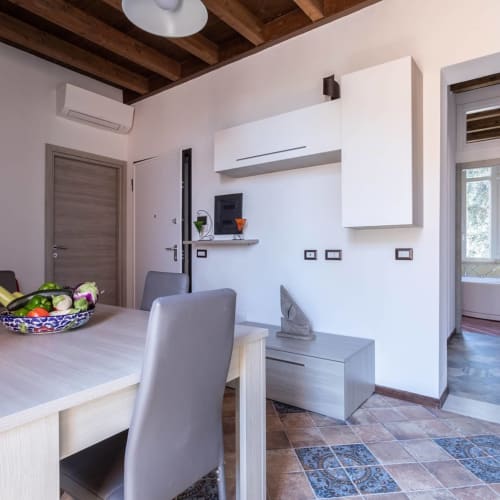 Moderna cucina-sala da pranzo nell'appartamento Maison Belle Époque, Oristano, con mobili bianchi, piastrelle decorative e atmosfera fresca