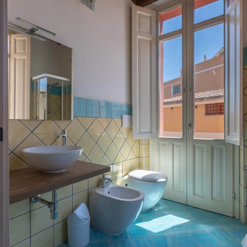 Bagno moderno con piastrelle turchesi, lavabo a coppa, bidet e toilet presso la Maison Belle Époque a Oristano, Italia