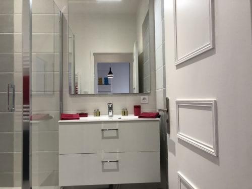 Salle de bains contemporaine à la Conciergerie Des Climats à Beaune avec vasque blanche, miroir, douche à l'italienne et accents rouges