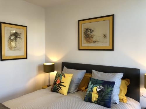 Chambre d'appartement à Beaune avec tête de lit noire, accents jaunes, coussins décorés, art animalier encadré et lampe de chevet