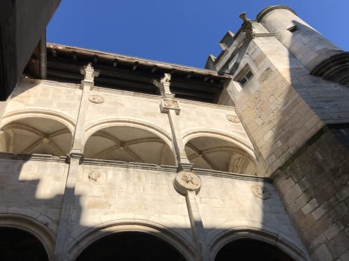 Architecture de pierre historique de la Conciergerie Des Climats à Beaune avec fenêtres en arche et détail de tour ornementale