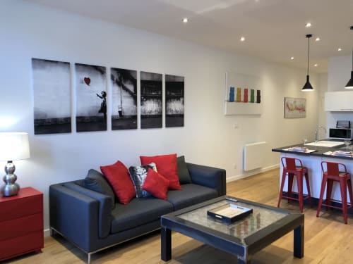 Appartement moderne à la Conciergerie Des Climats à Beaune avec canapé gris, accents rouges, table basse noire et mur style Banksy