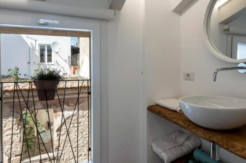 Modern bathroom with white vessel sink on wooden countertop at In Centro Da Viola, Olbia, with terrace view