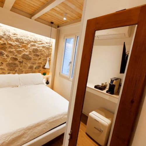 Modern bedroom at In Centro Da Viola Eco Design Rooms in Olba, Italy with stone wall accent and wooden ceiling