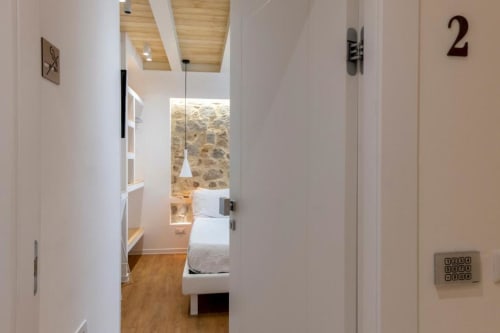 Modern hotel room 2 entrance at In Centro Da Viola, Olbia with wooden ceiling and stone wall view