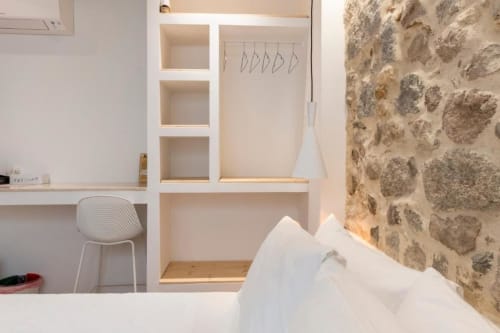 Modern hotel room at In Centro Da Viola with stone accent wall, built-in shelving, white bedding, and minimalist desk in