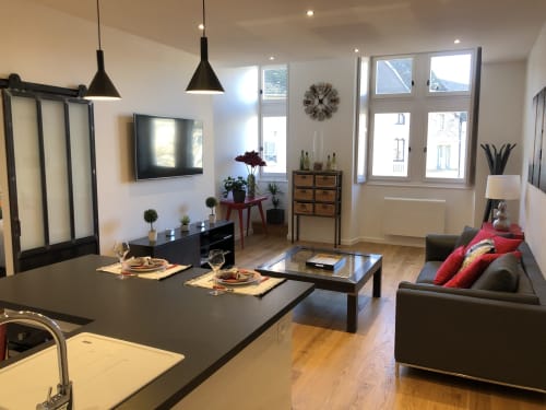 Appartement moderne à Beaune avec séjour ouvert, mobilier noir, vue sur la ville et luminaire suspendu contemporain