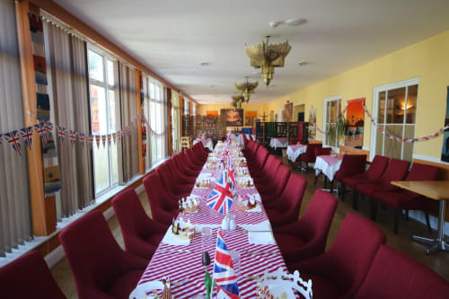 Long salle à manger de l'Hôtel La Trelade avec chaises bordeaux, drapeaux Union Jack et décoration patriotique des chemins de table