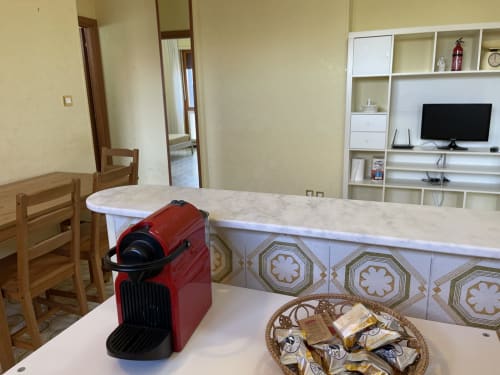 Cucina moderna presso Rigiariloo Home con macchina espresso rossa, piano in marmo e vista sulla zona living