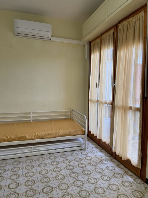 Luminosa camera da letto in appartamento presso Rigiariloo Home con letto singolo, aria condizionata, piastrelle decorative e vista sul giardino dalle finestre