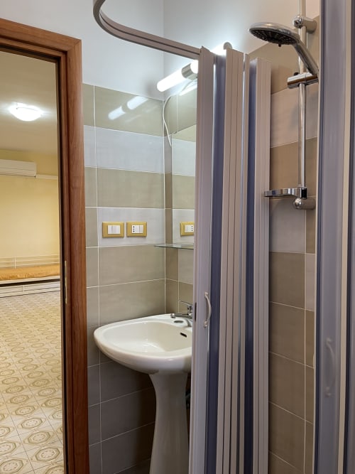 Bagno moderno presso Rigiariloo Home Apartments con doccia, lavabo a colonna e pareti piastrellate