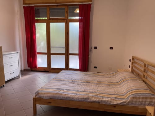Spaziosa camera da letto presso Rigiariloo Home Apartments con letto in legno, vista sul giardino e accesso al patio
