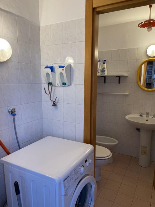 Bagno degli Apartments Rigiariloo con lavatrice, lavandino, WC e pareti piastrellate a San Giacomo degli Schiavoni