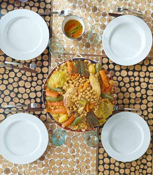 Overhead table setting at Riad Palau Marrakech with four place settings, vegetables dish, soup, and water glasses