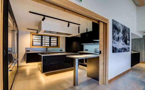 Cuisine moderne du Chalet Mont-Blanc avec mobilier noir, îlot central et vue sur les montagnes à Chamonix