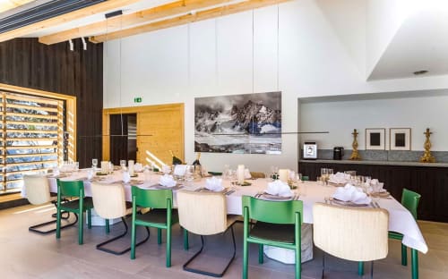 Salle à manger élégante du Chalet Mont-Blanc avec chaises vertes, couverts blancs et œuvres d'art paysager montagnard à Chamonix.