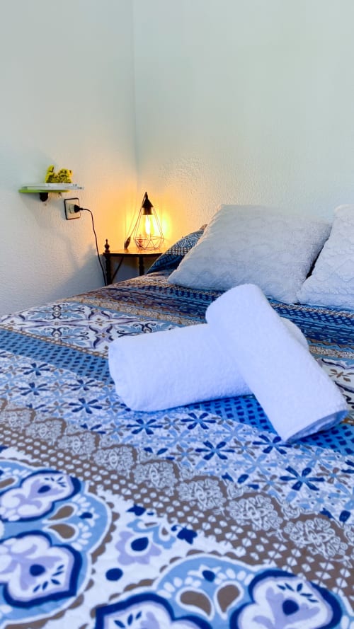Cómodo dormitorio en Casa Rural Villa del Jerte con ropa de cama decorativa azul, lámpara iluminada y almohadas blancas