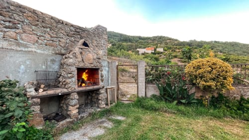 Chimenea de piedra rústica con fuego en terraza de villa con vistas a montañas y jardines, Casa Rural Villa del Jerte, El Torno
