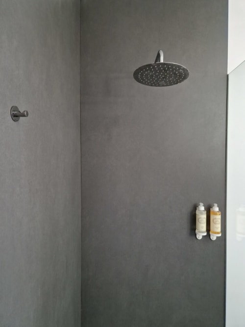 Chuveiro moderno na VAGO Alcântara Suites Lisboa com chuveiro de chuva e frascos de amenidades em parede com azulejo cinzento