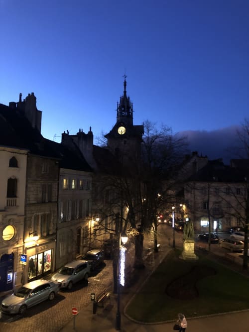 Centre-ville de Beaune au crépuscule, tour de l'église illuminée et bâtiments historiques en pierre, vue depuis la Conciergerie Des Climats