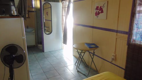 Chambre du gîte Caribgites à Sainte-Anne avec ventilateur, table, murs jaunes et vue sur jardin