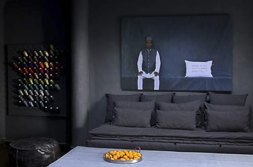 Modern lounge with dark sofa, interactive screen, and colorful art installation
