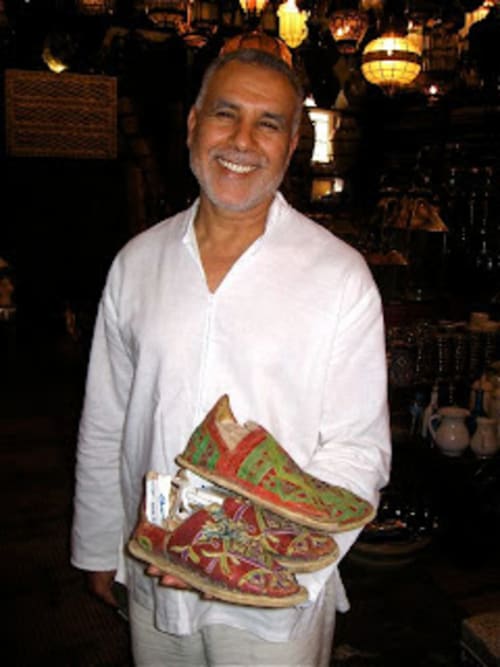 Smiling man holding decorative Moroccan slippers 