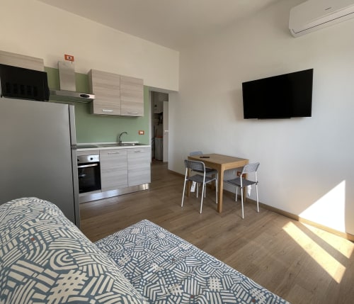 Moderno monolocale presso Rigiariloo Home Apartments con angolo cottura, tavolo da pranzo, letto e TV a parete a San Giacomo