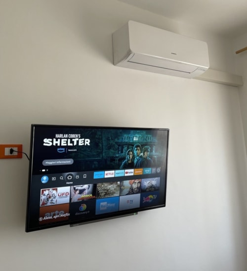 TV a schermo piatto montato a parete con app di streaming in moderno appartamento presso Rigiariloo Home Apartments, con aria condizionata bianca