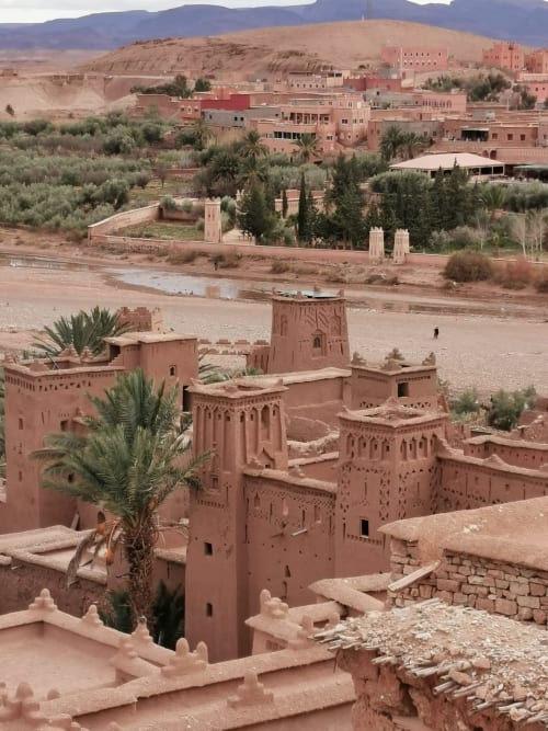 Kasbah aux bâtiments en terre rouge et rivière à Marrakech, Maroc