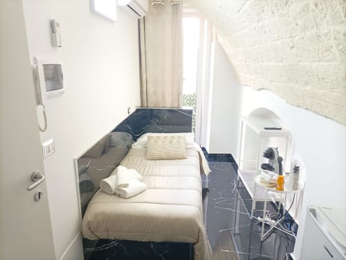 Compact bedroom at Newhouse hotel in Bari with white bedding, black marble floor, and balcony access