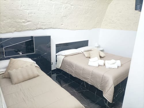 Camera doppia dell'hotel Newhouse Bari con letti in marmo scuro, biancheria bianca e parete in rilievo