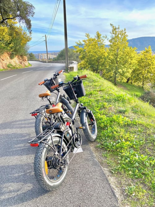 E-bikes parked on hillside road near Villa Colina in Mandelieu la Napoule, France with yellow trees and coastal views