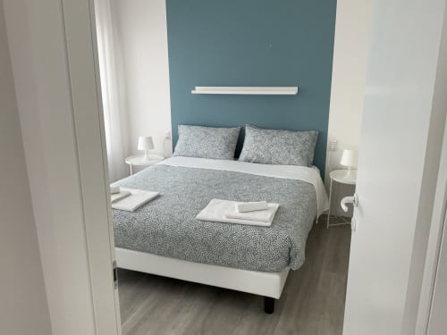 Modern bedroom in Lamar Suites Seafront Apartments with teal accent wall, queen bed, white nightstands, and contemporary