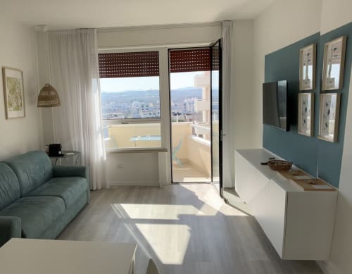 Modern suite with teal accent wall, sea view from balcony, contemporary furnishings at Lamar Suites Misano Adriatico
