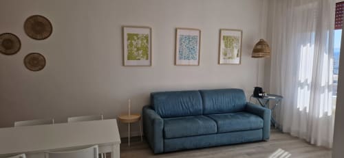 Modern living room in Lamar Suites Seafront Apartments with blue sofa, dining area, and framed artwork