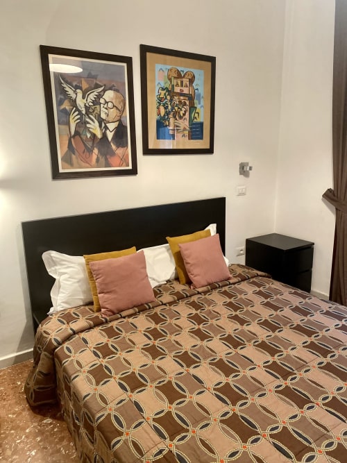 Standard double room at Casa Castagna B&B in Salerno with patterned bedspread, colorful cushions, and framed artwork above