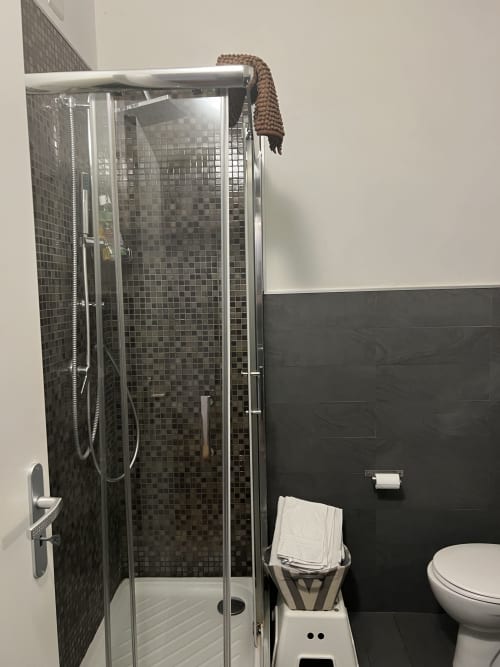 Modern bathroom with black mosaic tile shower, toilet, and white towels at Casa Castagna B&B in Salerno
