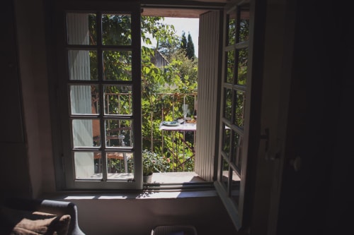 Open french doors reveal lush garden views and balcony at Ancienne Maison des Gardes in Lourmarin