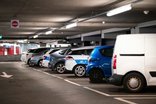Garaje de estacionamiento subterráneo del Hotel Fiori en Roma con varios autos estacionados e iluminación fluorescente.