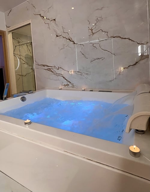 Jacuzzi rempli et en marche dans un appartement spa privé. Des bougies sur les bordures.