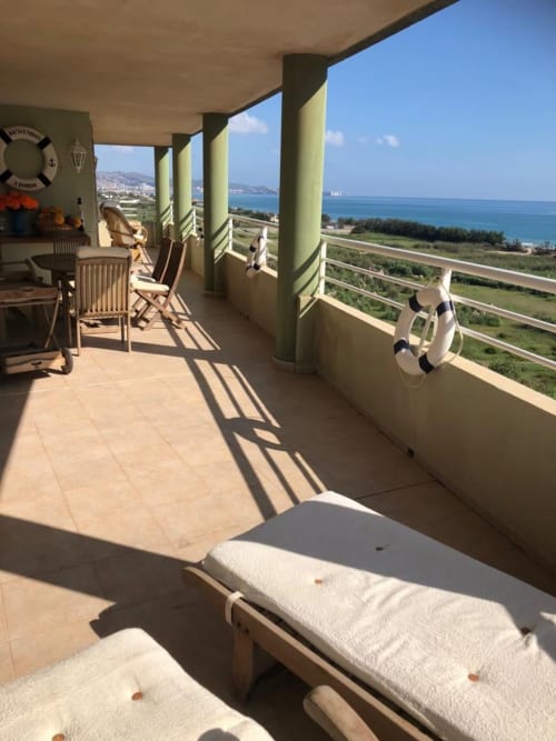 Seaside terrace with lounge chairs, dining area, and panoramic Mediterranean sea view at Retiro Playa apartment, Almagro.