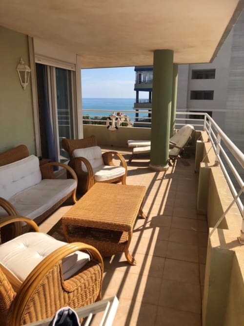 Sunny terrace at Retiro Playa & Spa Apartment with sea view, wicker furniture, and Mediterranean coastline vista