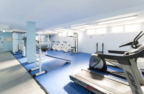 Modern fitness center with cardio equipment including treadmills and stationary bikes on blue flooring at Complejo Turístico