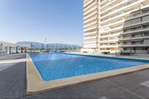 Large outdoor swimming pool at Complejo Turístico Retiro del Teatro in Almagro with modern apartment building and mountain