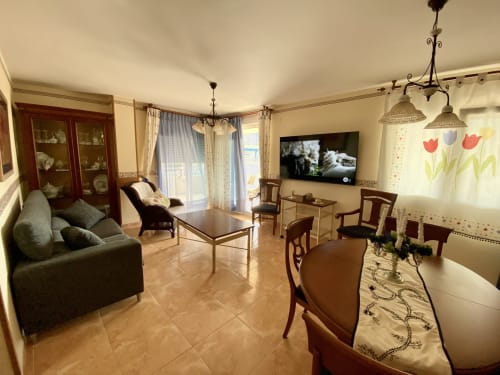 Spacious living area in Retiro Playa & Spa Apartment with sofa, TV, dining table, and balcony views in Almagro, Ciudad Real